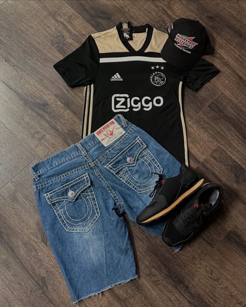 True Religion denim shorts, Ajax football jersey, black sneakers, and vintage race cap outfit grid