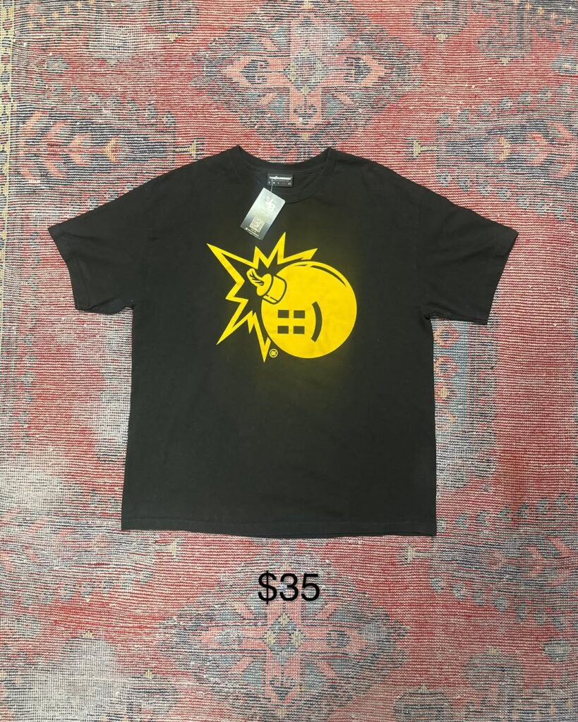 Graphic bomb yellow tee on patterned rug $35